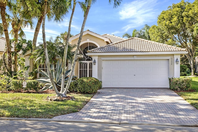 view of front of property featuring an attached garage, a tiled roof, decorative driveway, and stucco siding