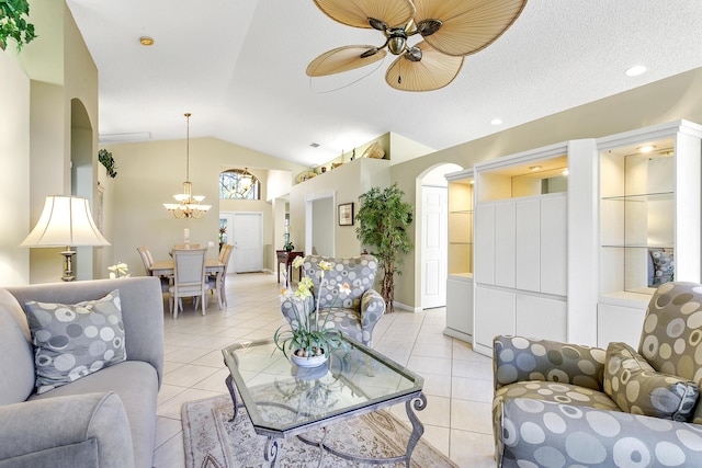 living room with arched walkways, a textured ceiling, light tile patterned flooring, ceiling fan with notable chandelier, and vaulted ceiling