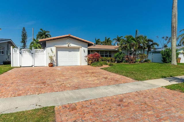 view of front of house featuring a tiled roof, an attached garage, a gate, decorative driveway, and a front yard