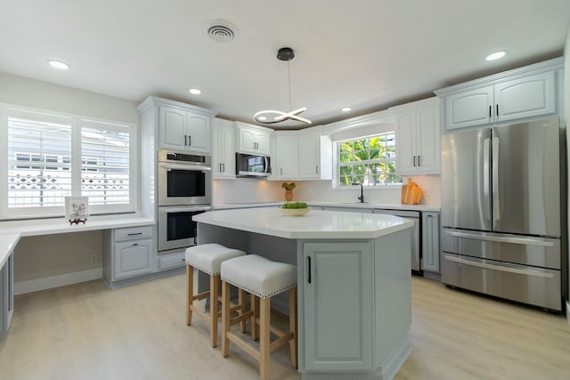 kitchen with stainless steel appliances, light countertops, a sink, and light wood finished floors