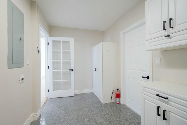 hallway featuring electric panel, baseboards, and light colored carpet