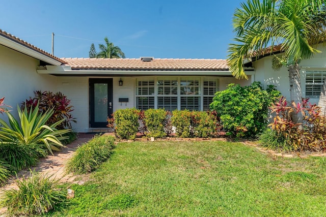 exterior space with a tile roof and a front lawn