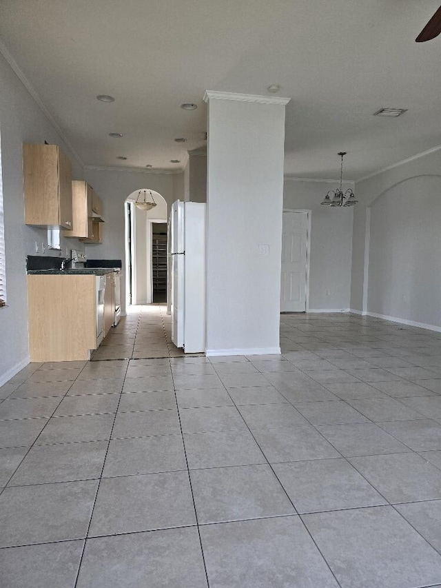 kitchen with dark countertops, arched walkways, crown molding, and freestanding refrigerator