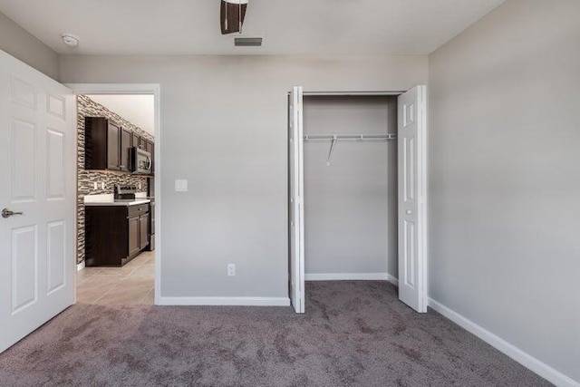 unfurnished bedroom with a closet, light carpet, visible vents, and baseboards