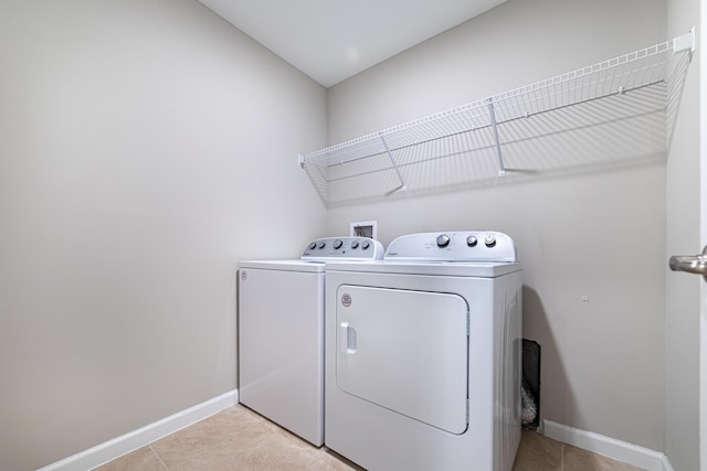 laundry room with laundry area, light tile patterned floors, baseboards, and washer and dryer