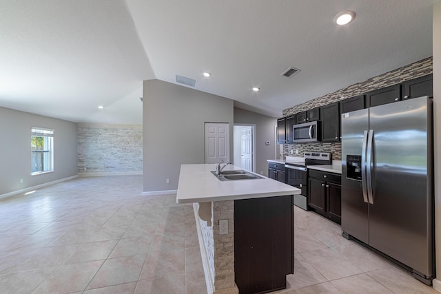 kitchen featuring a center island with sink, light countertops, appliances with stainless steel finishes, light tile patterned flooring, and a sink