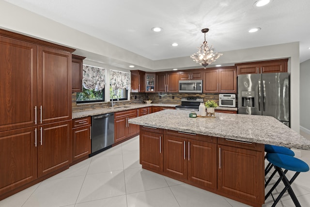 kitchen with a sink, stainless steel appliances, pendant lighting, tasteful backsplash, and a center island