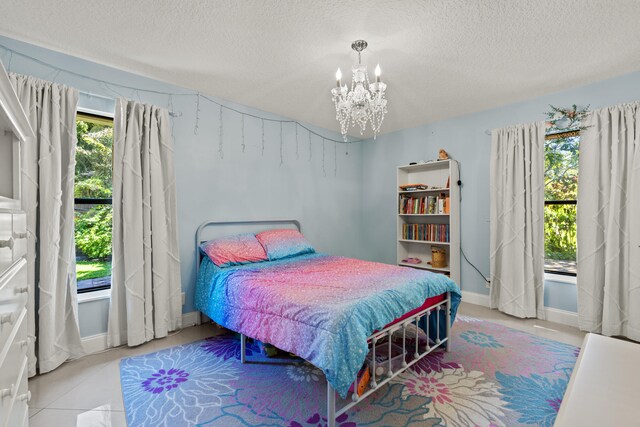 bedroom featuring tile patterned flooring, baseboards, a textured ceiling, and an inviting chandelier