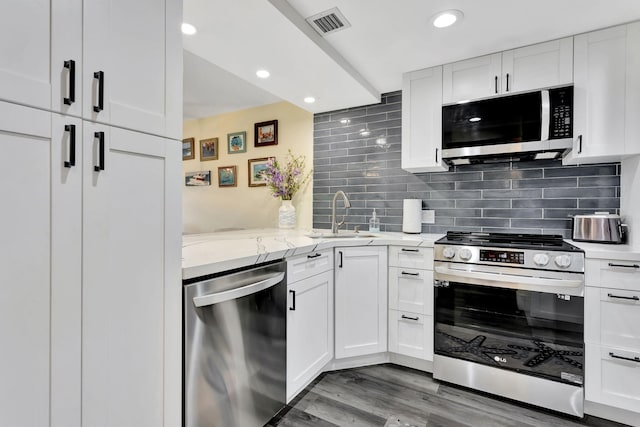 kitchen with stainless steel appliances, a sink, visible vents, white cabinets, and tasteful backsplash