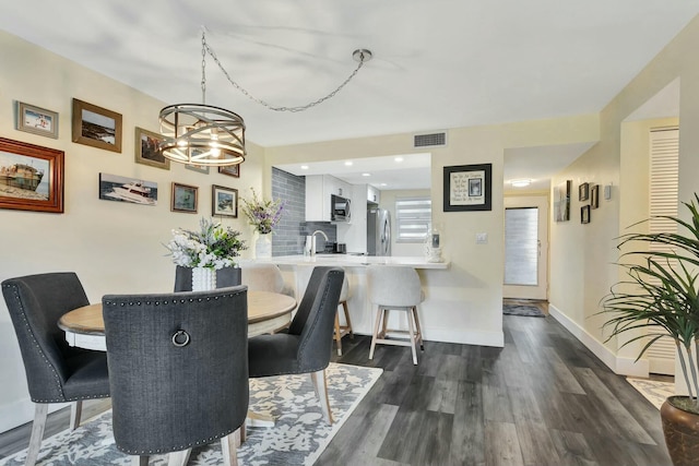 dining room featuring an inviting chandelier, dark wood finished floors, visible vents, and baseboards