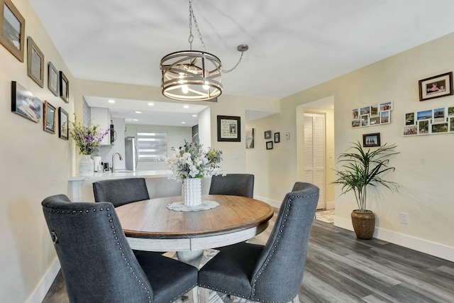 dining room with a notable chandelier, baseboards, wood finished floors, and recessed lighting