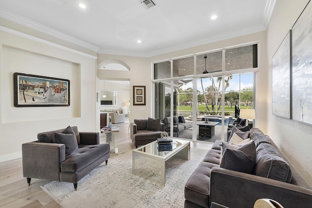 living room with wood finished floors, visible vents, a towering ceiling, baseboards, and ornamental molding