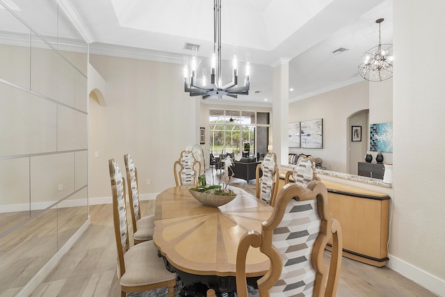 dining space with an inviting chandelier, arched walkways, and a raised ceiling