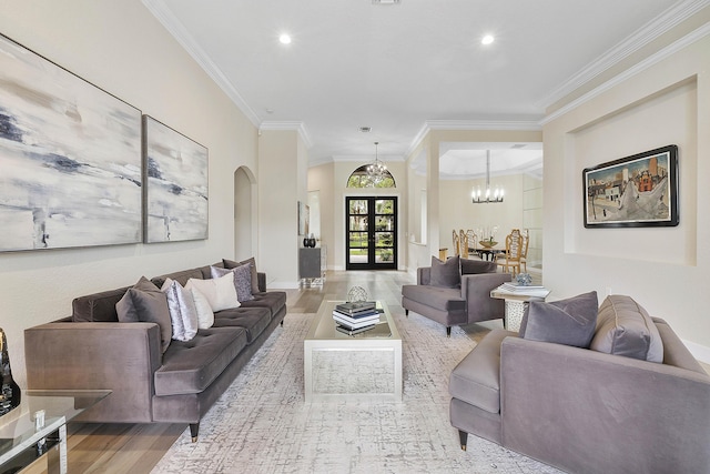 living area with arched walkways, wood finished floors, an inviting chandelier, crown molding, and recessed lighting