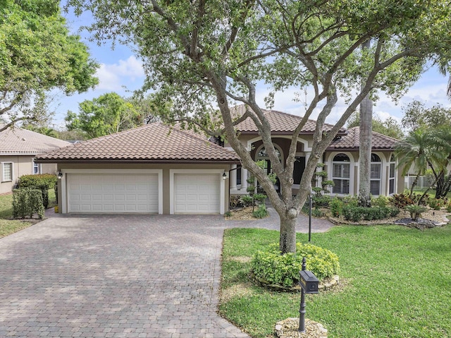 mediterranean / spanish-style home with decorative driveway, a tiled roof, an attached garage, and stucco siding