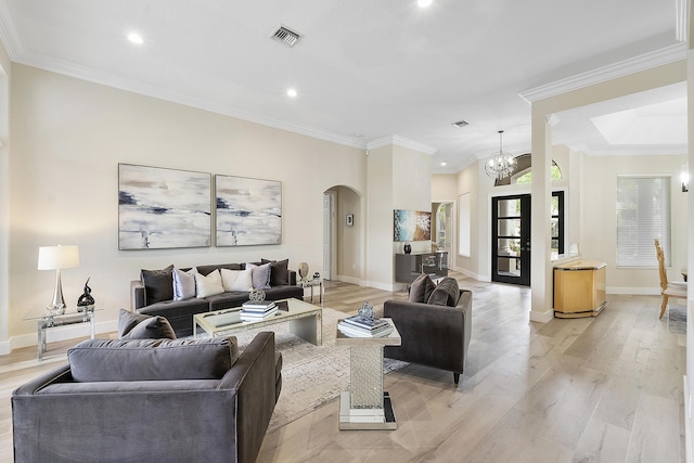 living area featuring arched walkways, visible vents, baseboards, light wood-style floors, and ornamental molding