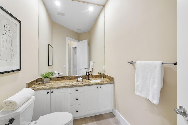 bathroom with visible vents, toilet, vanity, wood finished floors, and baseboards