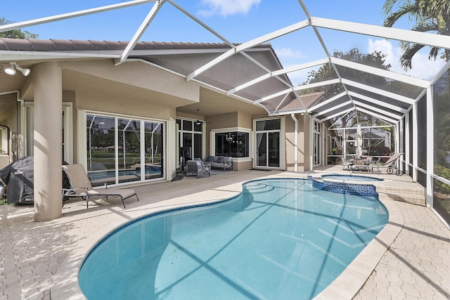 view of pool featuring a patio, glass enclosure, an outdoor living space, and a pool with connected hot tub