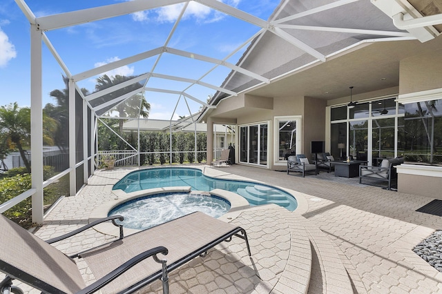 view of swimming pool with a pool with connected hot tub, glass enclosure, a patio area, and a ceiling fan