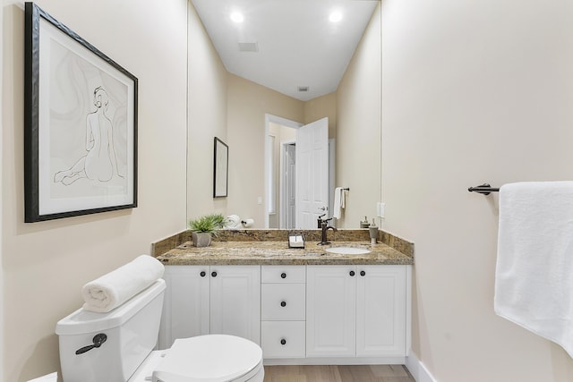 bathroom with visible vents, toilet, vanity, wood finished floors, and baseboards