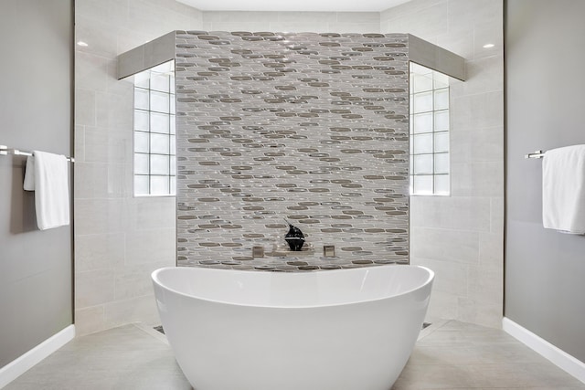 full bathroom with a freestanding tub, tile patterned flooring, and baseboards