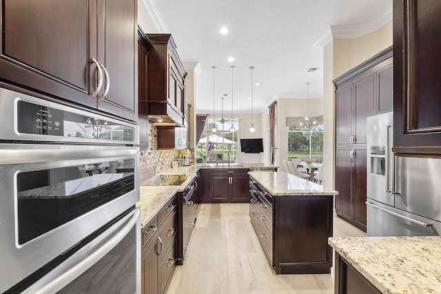 kitchen with stainless steel appliances, backsplash, ornamental molding, a kitchen island, and light stone countertops