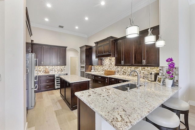 kitchen featuring beverage cooler, a peninsula, a sink, freestanding refrigerator, and stovetop