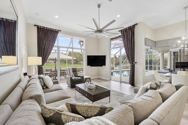 living room featuring recessed lighting, ceiling fan with notable chandelier, baseboards, light wood-type flooring, and crown molding