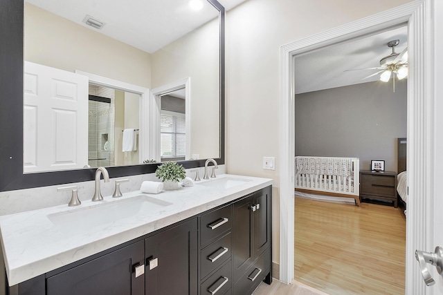 full bath with double vanity, a stall shower, a sink, and wood finished floors