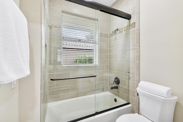 bathroom with toilet and shower / bath combination with glass door