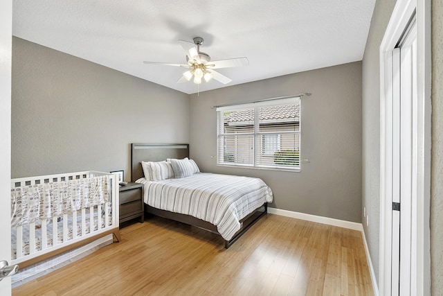 bedroom featuring a ceiling fan, light wood-type flooring, and baseboards