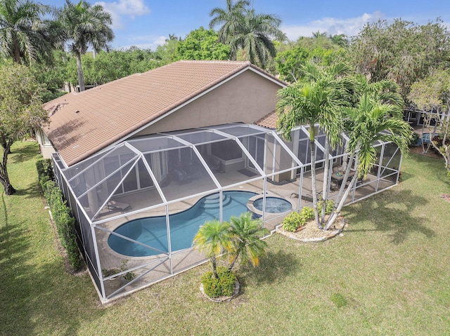 pool featuring a patio, a yard, glass enclosure, and an in ground hot tub