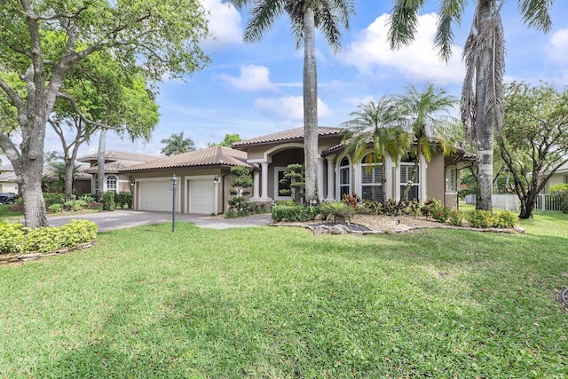 mediterranean / spanish-style house with aphalt driveway, a garage, a tiled roof, stucco siding, and a front lawn