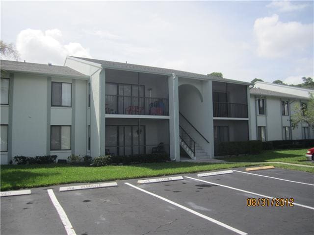 view of building exterior featuring uncovered parking and stairway