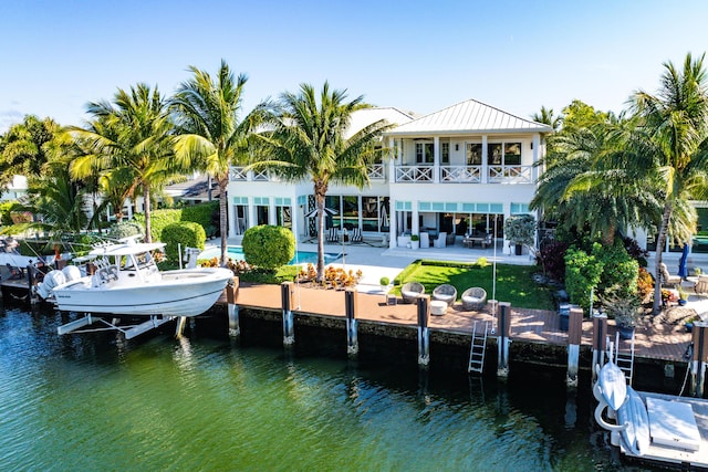 dock area featuring a water view, a balcony, an outdoor pool, boat lift, and a patio area