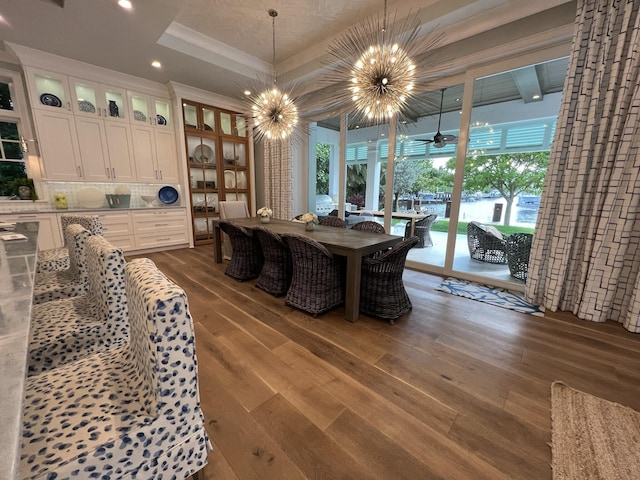 dining area featuring ceiling fan with notable chandelier, a raised ceiling, recessed lighting, and dark wood-style floors