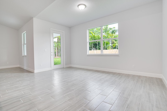 empty room with light wood-style floors, plenty of natural light, and baseboards