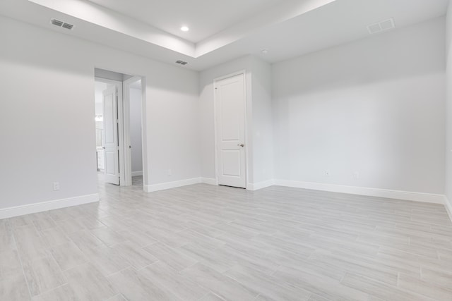 empty room featuring light wood-style floors, recessed lighting, visible vents, and baseboards