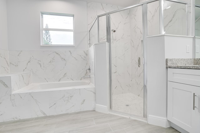 bathroom with a garden tub, a marble finish shower, and vanity