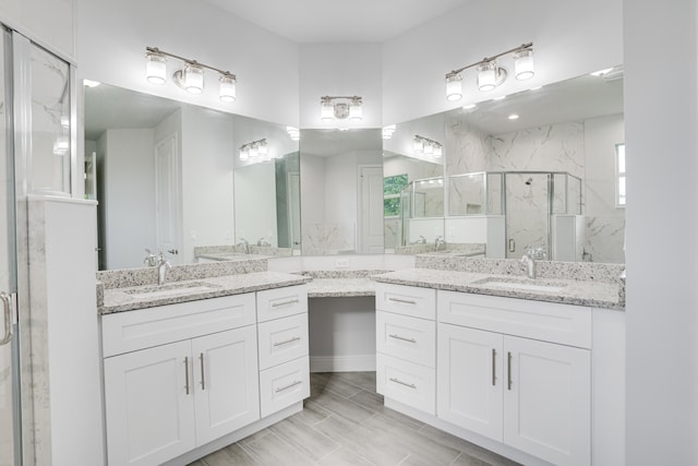 full bath with a marble finish shower, two vanities, and a sink