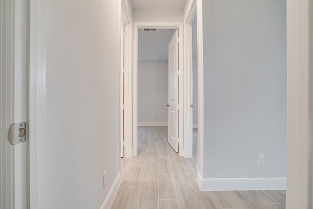 corridor with baseboards, visible vents, and wood finish floors