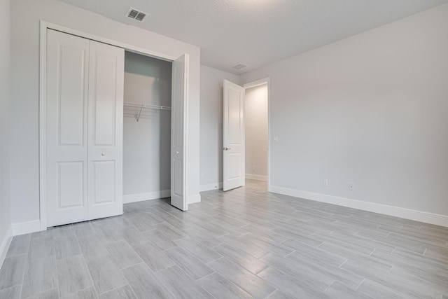 unfurnished bedroom with light wood-style floors, a closet, visible vents, and baseboards