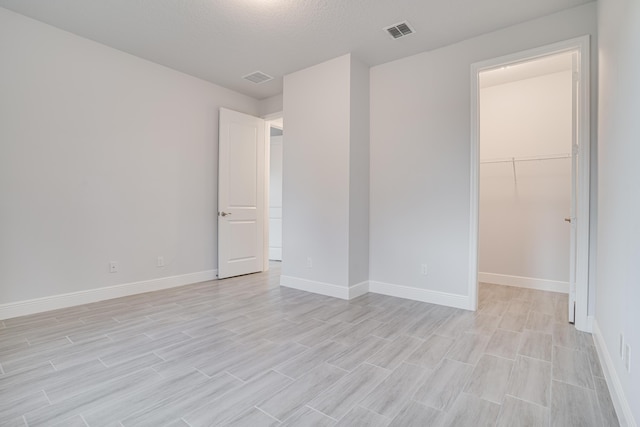 spare room with light wood-style floors, visible vents, and baseboards