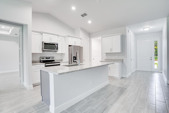 kitchen featuring wood finish floors, a center island with sink, stainless steel appliances, white cabinets, and a sink