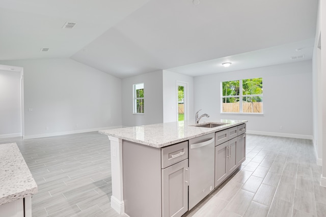 kitchen featuring gray cabinetry, a sink, open floor plan, light stone countertops, and dishwasher