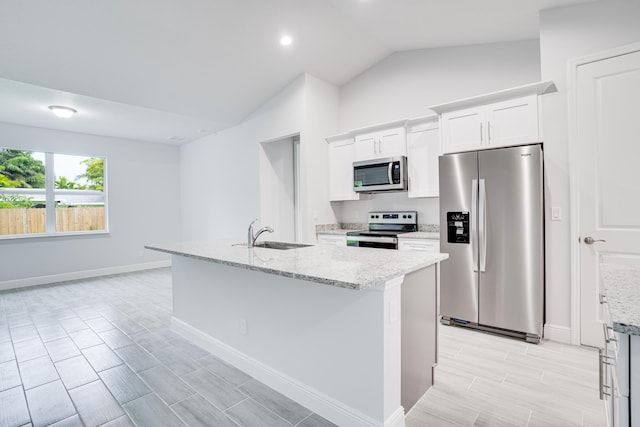 kitchen featuring stainless steel appliances, a sink, white cabinetry, vaulted ceiling, and light stone countertops