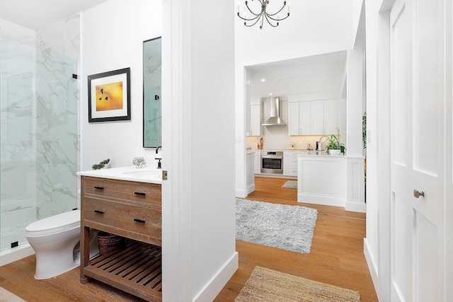 bathroom with toilet, wood finished floors, a marble finish shower, baseboards, and vanity