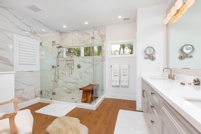 bathroom with a marble finish shower, visible vents, recessed lighting, wood finished floors, and a sink