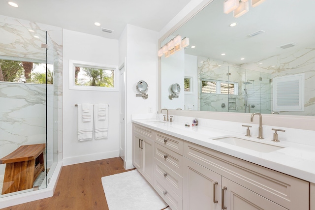 bathroom featuring a sink, a marble finish shower, visible vents, and wood finished floors