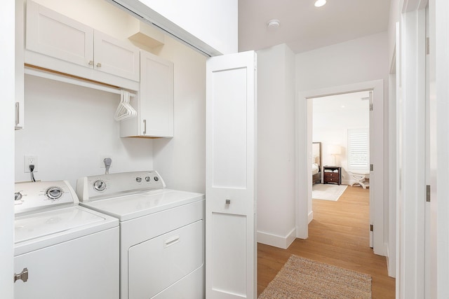 washroom with washer and dryer, light wood-style flooring, cabinet space, and baseboards